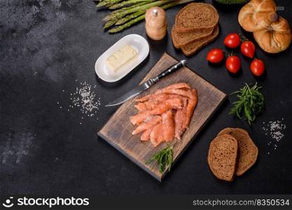 Beautiful delicious red fish slices on a wooden cutting board against a dark concrete background. Beautiful delicious red fish slices on a wooden cutting board
