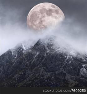 Beautiful digital composite image of Supermoon above mountain range giving very surreal fantasy look to the dramatic landscape image