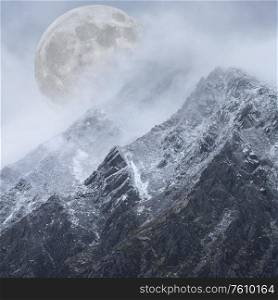 Beautiful digital composite image of Supermoon above mountain range giving very surreal fantasy look to the dramatic landscape image