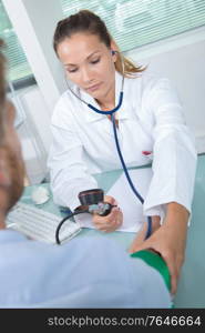 beautiful doctor testing blood pressure to a senior patient