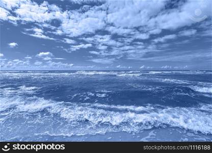 Beautiful dramatic seascape with stormy sea. View on Baltic sea, sand beach and sky with clouds. Summer background. Trendy banner toned in classic blue - color of the 2020 year. Beautiful dramatic seascape with stormy sea. View on Baltic sea, sand beach and sky with clouds. Summer background.