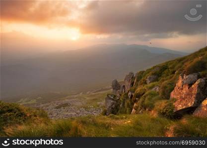 Beautiful dramatic sunset in the mountains. Landscape with sun light shining through orange clouds