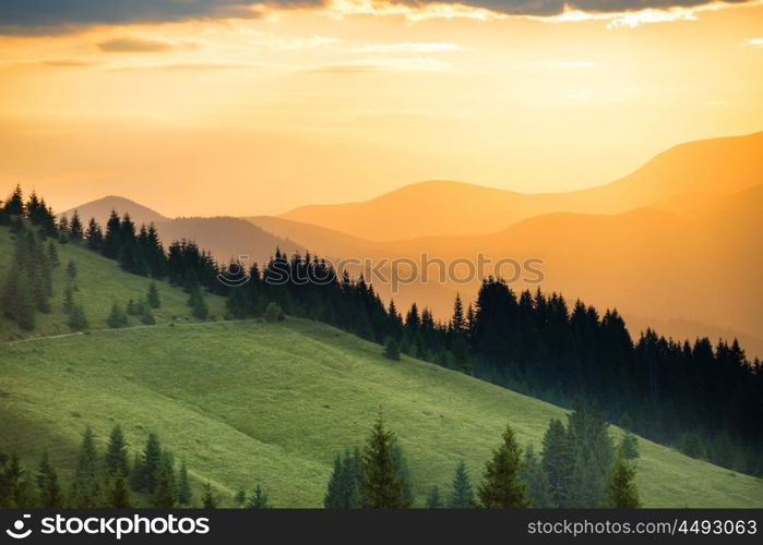 Beautiful dramatic sunset in the mountains. Landscape with sun shining through orange clouds