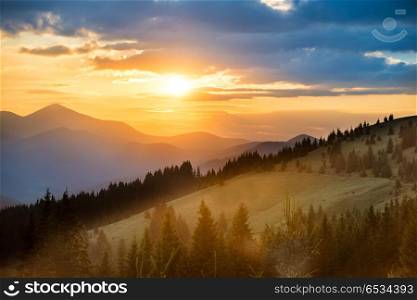 Beautiful dramatic sunset in the mountains. Landscape with sun shining through orange clouds. Beautiful sunset in the mountains