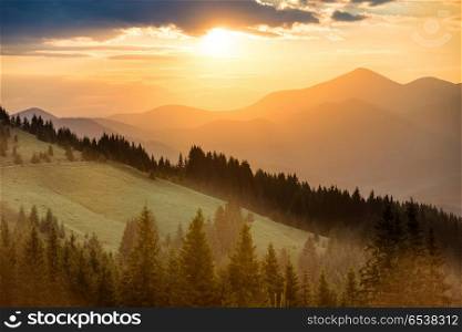 Beautiful dramatic sunset in the mountains. Landscape with sun shining through orange clouds. Beautiful sunset in the mountains