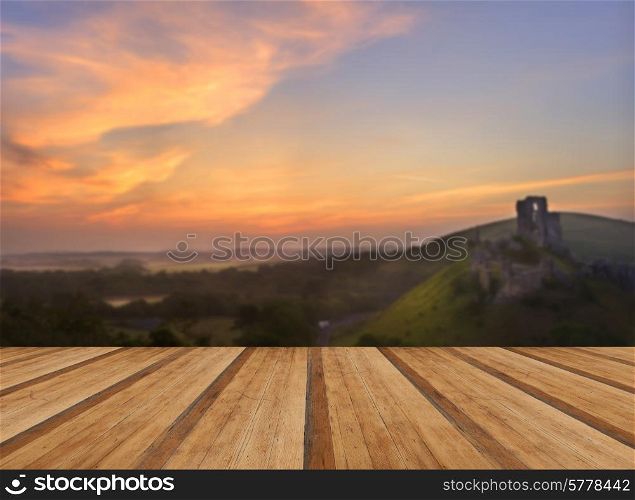 Beautiful dreamy fairytale castle ruins against romantic colorful sunrise with wooden planks floor