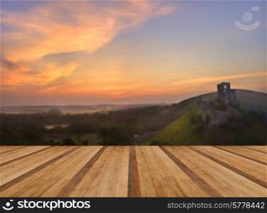 Beautiful dreamy fairytale castle ruins against romantic colorful sunrise with wooden planks floor