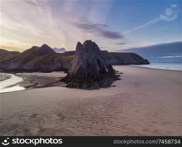 Beautiful drone landscape image of Three Cliffs Bay in South Wales during Summer sunrise