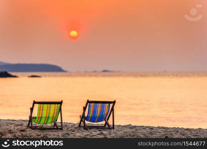 Beautiful early sunset over two deck chairs on the sandy tropical beach and Wave of the sea on the sand beach the horizon Summer time at hat sai kaew beach in Chanthaburi Thailand.