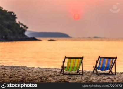Beautiful early sunset over two deck chairs on the sandy tropical beach and Wave of the sea on the sand beach the horizon Summer time at hat sai kaew beach in Chanthaburi Thailand.