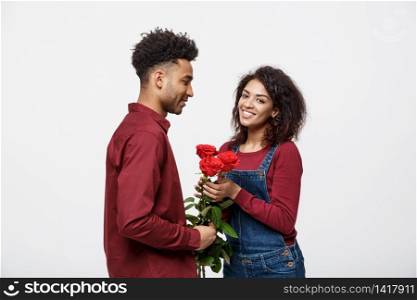 Beautiful elegant couple is hugging and smiling, on gray background. Girl is holding roses.. Beautiful elegant couple is hugging and smiling, on gray background. Girl is holding roses