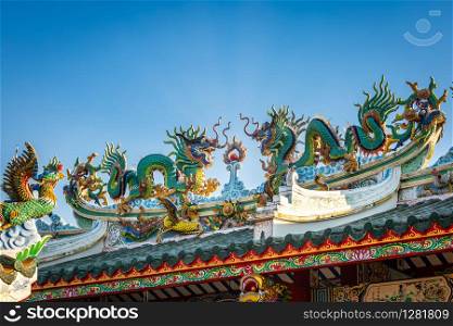 Beautiful Elegant double golden dragon statue on the roof of on a temple for Chinese New Year Festival at Chinese shrine with blue sky.