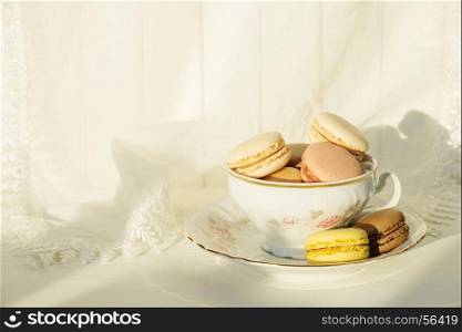 Beautiful elegant porcelain cup filled with almond cookies, on the background of white lace fabric