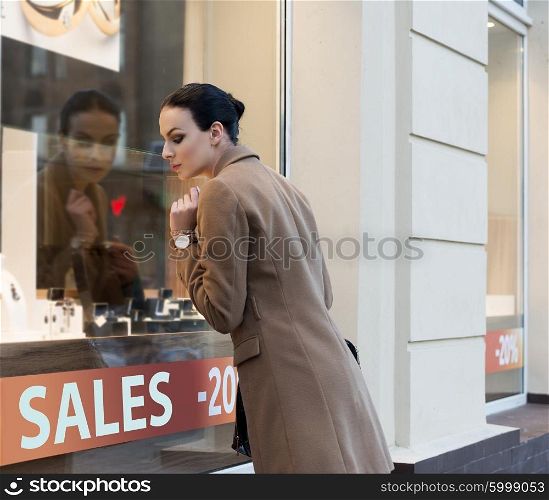 beautiful elegant woman , outdoor for shopping , looking at jewellery windiw shop with desire.