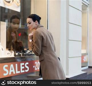 beautiful elegant woman , outdoor for shopping , looking at jewellery windiw shop with desire.