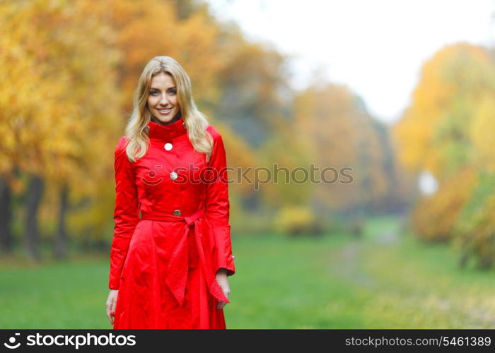 Beautiful elegant woman standing in a park in autumn