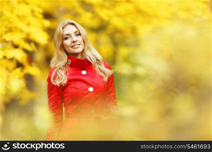 Beautiful elegant woman standing in a park in autumn