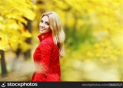 Beautiful elegant woman standing in a park in autumn