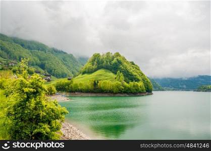 Beautiful emerald mountain lake Lungern in Switzerland under low clouds