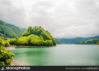 Beautiful emerald mountain lake Lungern in Switzerland under low clouds