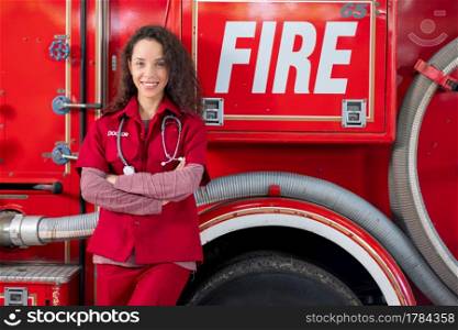 Beautiful emergency doctor woman stand and lean fire truck with smiling. Concept of supporting people during emergency of disaster event.