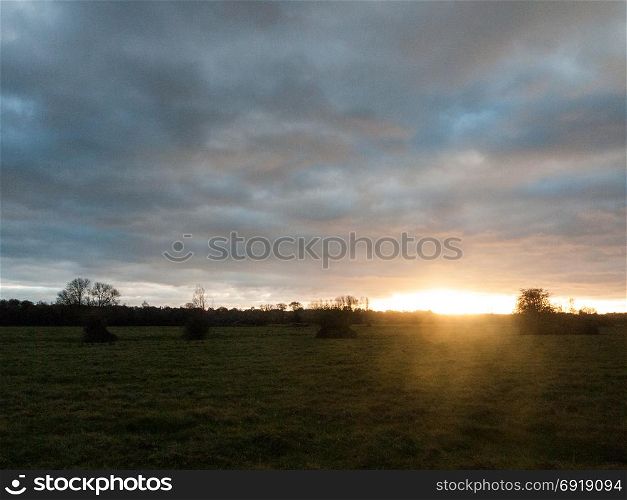 beautiful empty autumn cold countryside trees grass dramatic sky sun set gold ray; essex; england; uk