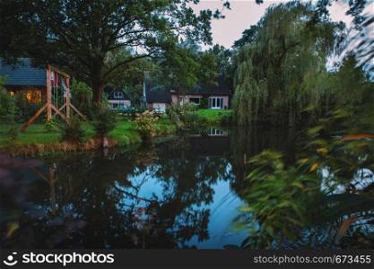 Beautiful evening in Netherlands. Nice Dutch yard with canal and plants