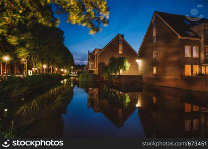 Beautiful evening in Uithoorn. Dutch houses and canal with plants, Netherlands
