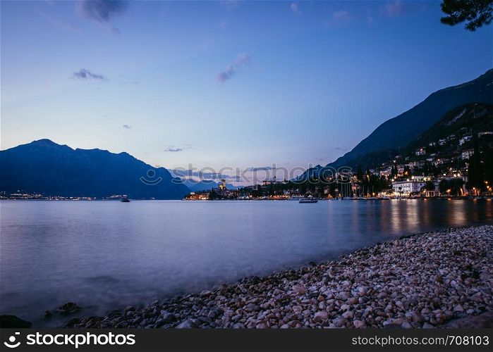 Beautiful evening scenery on the beach with cute little village, lago di garda, Italy.