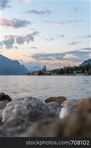 Beautiful evening scenery with cute little village, lago di garda, Italy. Stones in the foreground.