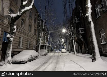 Beautiful evening twilight winter cityscape in the center of Lviv city, Ukraine. The car is covered with snow.