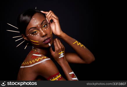 Beautiful exotic African female fashion face with tribal yellow red and white makeup cosmetics and sticks in hair.