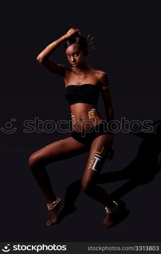 Beautiful exotic African female fashion with tribal yellow red and white cultural makeup cosmetics and sticks in hair, in cultural dance position.