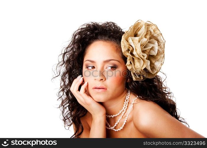 Beautiful face of a tanned Caucasian Hispanic woman with clear skin, wearing a pearl necklace and a fake flower in curly hair, isolated.