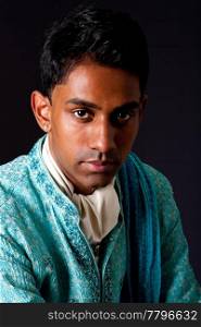 Beautiful face of an Indian Hindu young man with earring wearing blue Dhoti. Portrait of handsome Desi male, isolated.