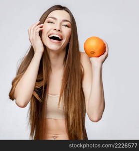 Beautiful Face of Young Woman with Clean Fresh Skin close up. Beauty Portrait. Beautiful Spa Woman Smiling. Perfect Fresh Skin. Pure Beauty Model. Youth and Skin Care Concept. Beautiful Woman with Clean Fresh Skin holding orange