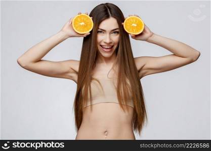 Beautiful Face of Young Woman with Clean Fresh Skin close up. Beauty Portrait. Beautiful Spa Woman Smiling. Perfect Fresh Skin. Pure Beauty Model. Youth and Skin Care Concept. Beautiful Woman with Clean Fresh Skin holding orange