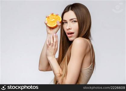 Beautiful Face of Young Woman with Clean Fresh Skin close up. Beauty Portrait. Beautiful Spa Woman Smiling. Perfect Fresh Skin. Pure Beauty Model. Youth and Skin Care Concept. Beautiful Woman with Clean Fresh Skin holding orange