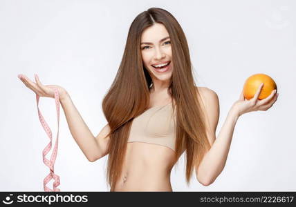 Beautiful Face of Young Woman with Clean Fresh Skin close up. Beauty Portrait. Beautiful Spa Woman Smiling. Perfect Fresh Skin. Pure Beauty Model. Youth and Skin Care Concept. Beautiful Woman with Clean Fresh Skin holding orange