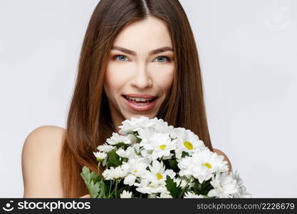 Beautiful Face of Young Woman with Clean Fresh Skin close up. Beauty Portrait. Beautiful Spa Woman Smiling. Perfect Fresh Skin. Pure Beauty Model. Youth and Skin Care Concept. Beautiful Woman with Clean Fresh Skin holding flowers