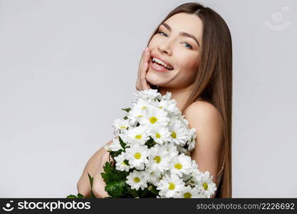 Beautiful Face of Young Woman with Clean Fresh Skin close up. Beauty Portrait. Beautiful Spa Woman Smiling. Perfect Fresh Skin. Pure Beauty Model. Youth and Skin Care Concept. Beautiful Woman with Clean Fresh Skin holding flowers