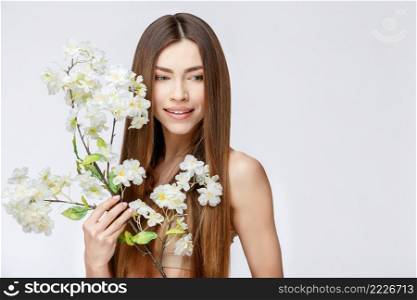 Beautiful Face of Young Woman with Clean Fresh Skin close up. Beauty Portrait. Beautiful Spa Woman Smiling. Perfect Fresh Skin. Pure Beauty Model. Youth and Skin Care Concept. Beautiful Woman with Clean Fresh Skin holding flowers