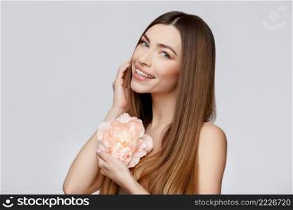 Beautiful Face of Young Woman with Clean Fresh Skin close up. Beauty Portrait. Beautiful Spa Woman Smiling. Perfect Fresh Skin. Pure Beauty Model. Youth and Skin Care Concept. Beautiful Woman with Clean Fresh Skin holding flowers