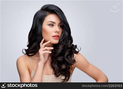 Beautiful Face of Young Woman with Clean healthy curly hair close up isolated on gray background. Beautiful Woman. Perfect Fresh Skin. Pure Beauty Model. Youth Skin and Hair Care Concept. Beautiful Young Woman with Clean healthy curly hair