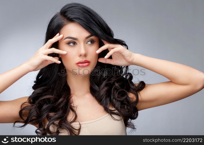 Beautiful Face of Young Woman with Clean healthy curly hair close up isolated on gray background. Beautiful Woman. Perfect Fresh Skin. Pure Beauty Model. Youth Skin and Hair Care Concept. Beautiful Young Woman with Clean healthy curly hair