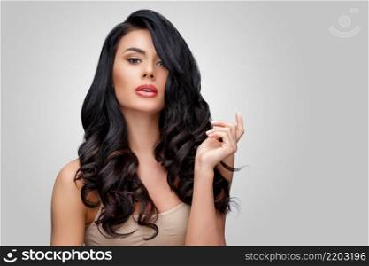 Beautiful Face of Young Woman with Clean healthy curly hair close up isolated on gray background. Beautiful Woman. Perfect Fresh Skin. Pure Beauty Model. Youth Skin and Hair Care Concept. Beautiful Young Woman with Clean healthy curly hair