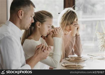 beautiful family praying together before eating