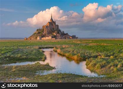 Beautiful famous Mont Saint Michel at sunset with reflection in the canal on the water meadows, Normandy, France. Mont Saint Michel at sunset, Normandy, France