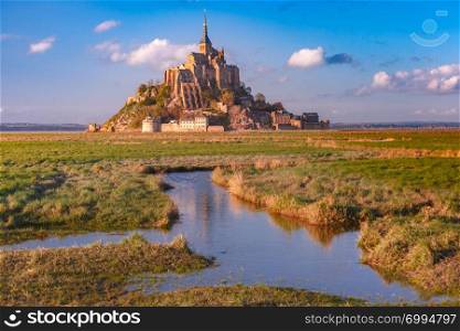 Beautiful famous Mont Saint Michel at sunset with reflection in the canal on the water meadows, Normandy, France. Mont Saint Michel at sunset, Normandy, France