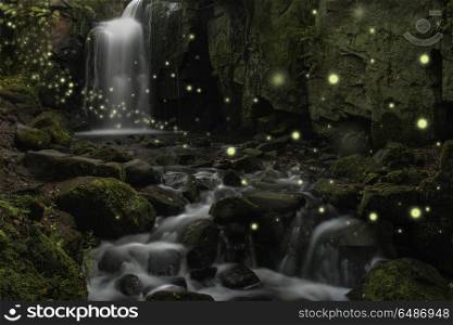 Beautiful fantasy image of fireflies over stream in rocky canyon. Beautiful ethereal fantasy image of fireflies over stream in rocky canyon landscape at dusk